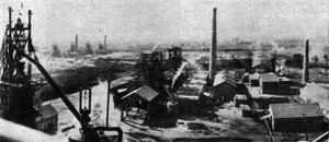 Old black and white photo of an early steel works with furnaces and chimneys