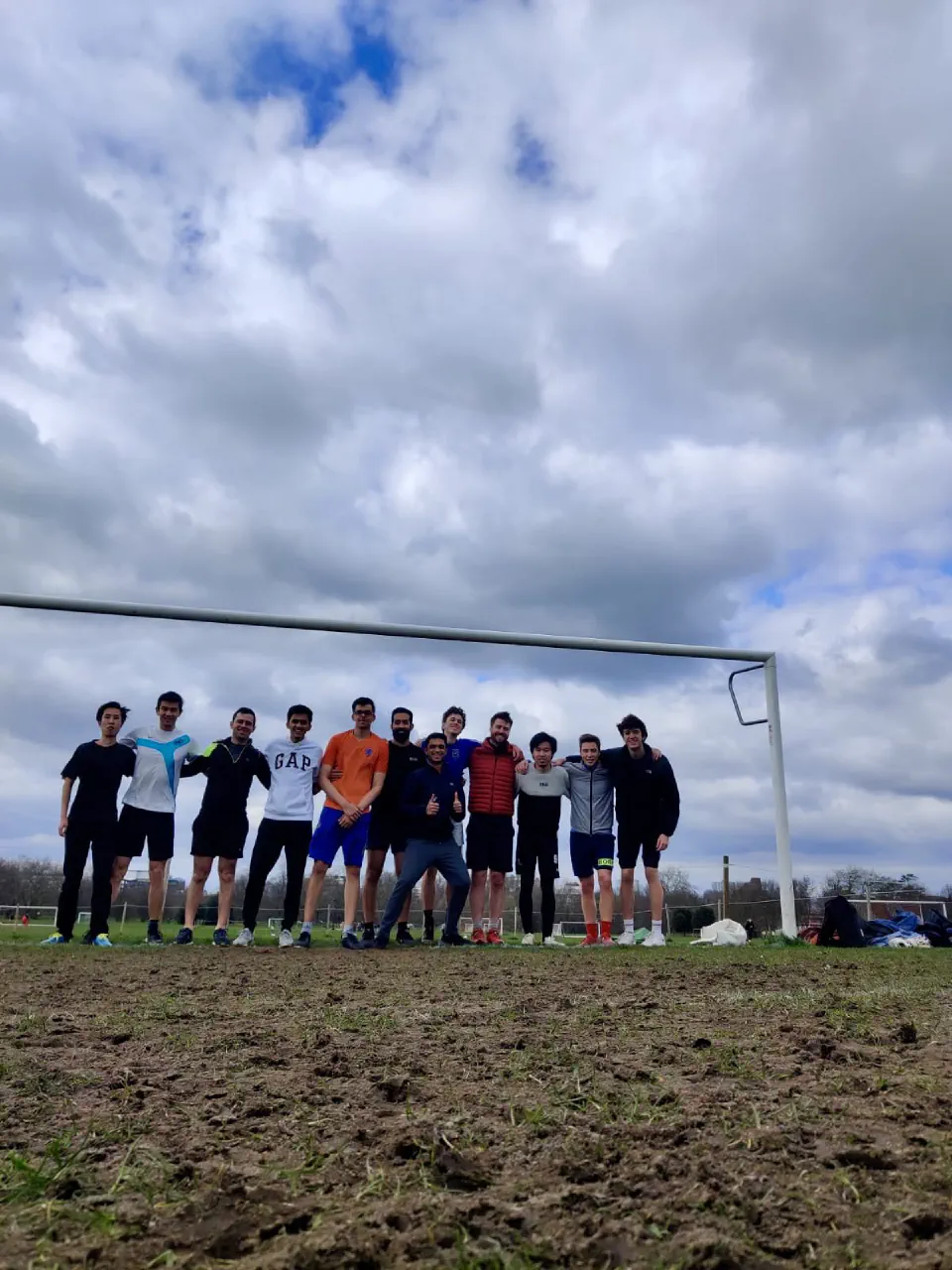 Team photo in front of a goal under a cloudy sky